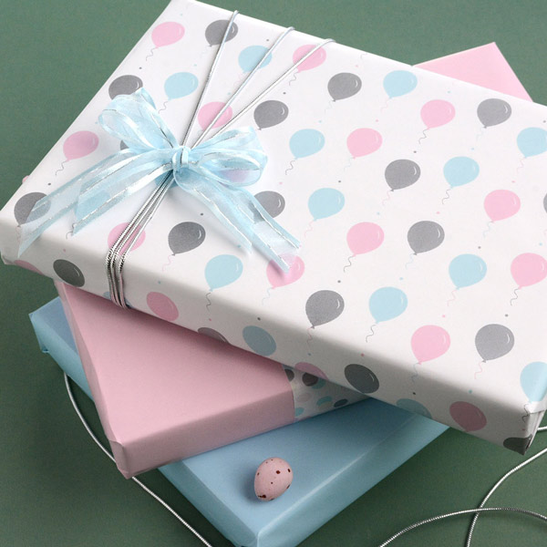 A stack of 3 wrapped gifts in shades of pink, blue and silver