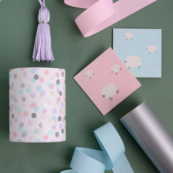 A pastel themed flat-lay displaying wrapping paper, ribbon and gift cards