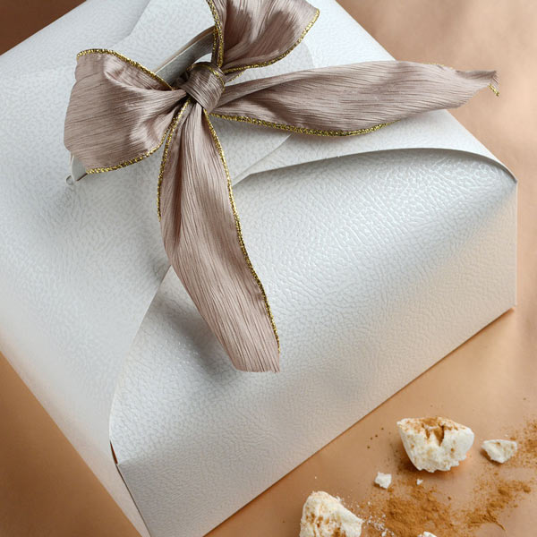 White Italian cake box wrapped with wide taupe-gold ribbon