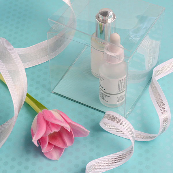 Clear box containing serums with white-silver ribbons and a tulip